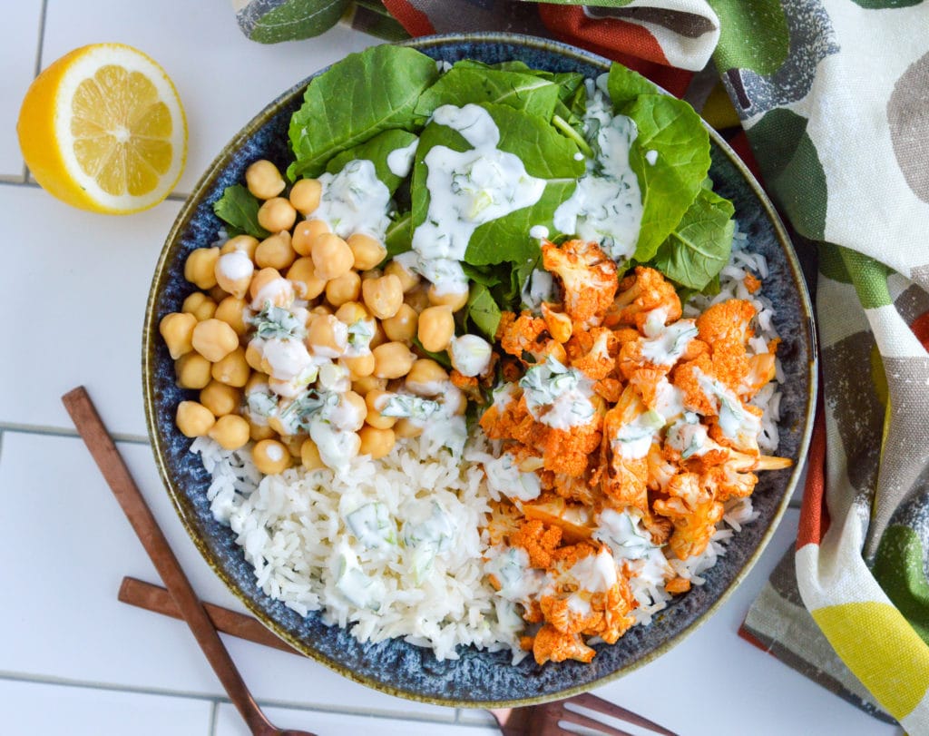 This simple yet luxurious bowl brings together two favorites-- buffalo cauliflower and rice. It’s topped with a delicious homemade herby yogurt sauce, making it the perfect option for a packed lunch or a simple make-ahead dinner. #ricebowl #buffalocauliflower #mealprep #vegetarian